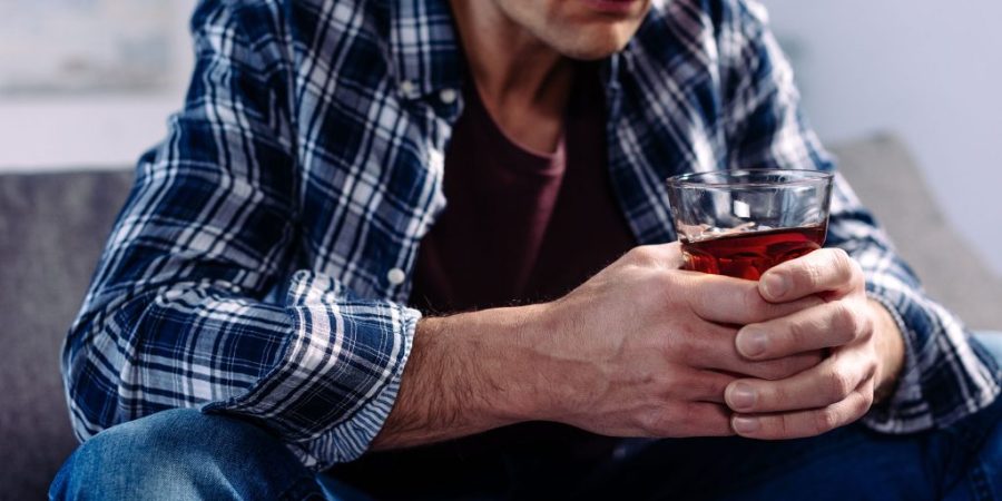 Man holding an alcoholic drink and contemplating suicide